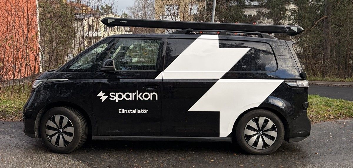 Sparkons firmabil — en svart elektrisk Volkswagen ID. Buzz med Sparkon-symbolen på sidan, redo för uppdrag i Stockholm